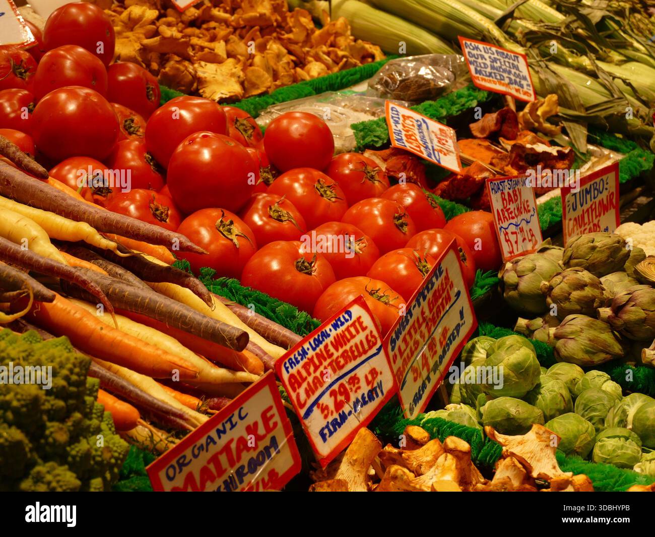 SEATTLE - 18 septembre 2025 - produits frais de la ferme colorés, y compris tomates vibrantes, champignons maitake biologiques, carottes croquantes, bébés artichauts et maïs Banque D'Images