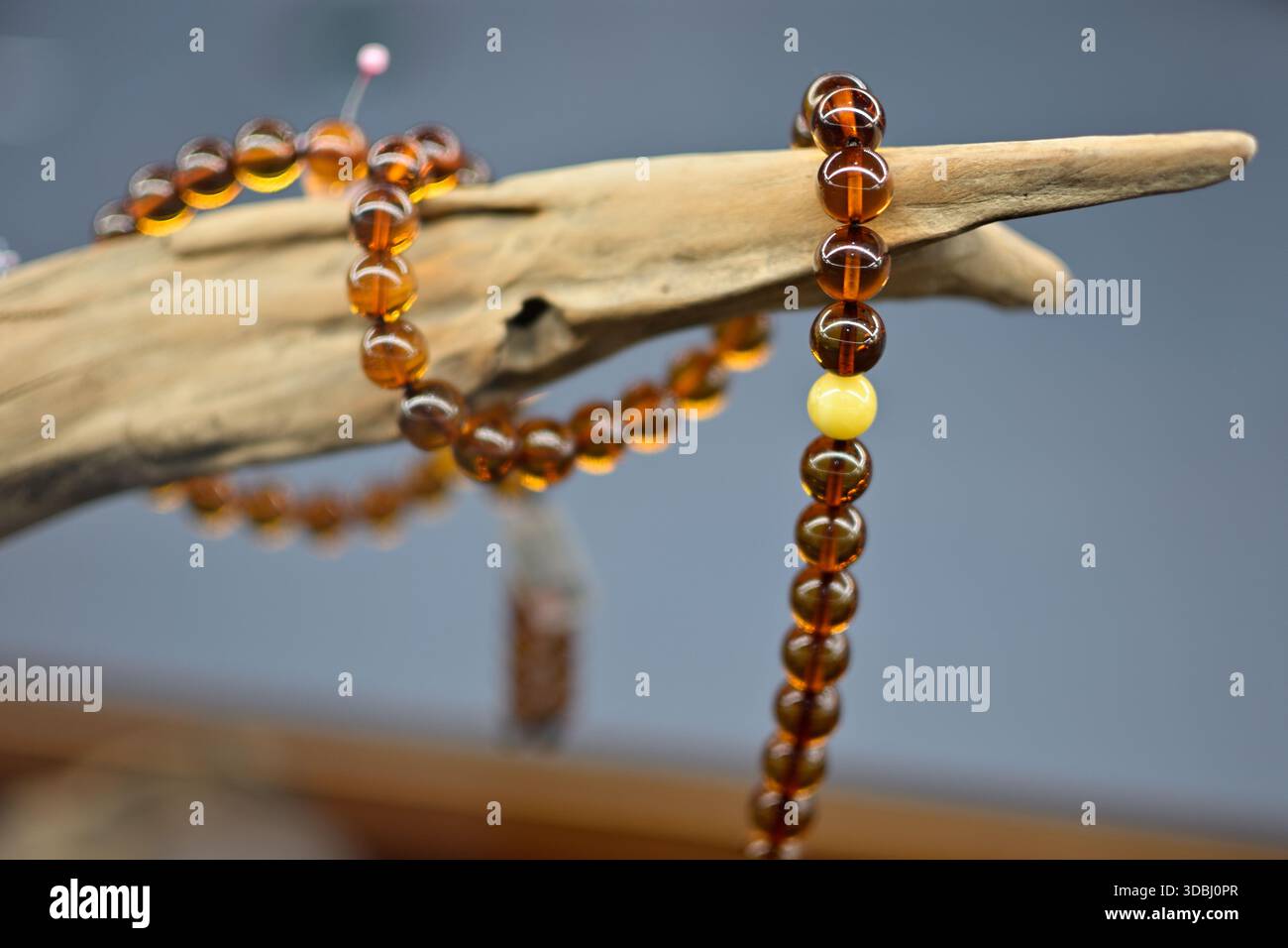 Perles de prière ambre drapées sur un morceau de bois flotté. Banque D'Images