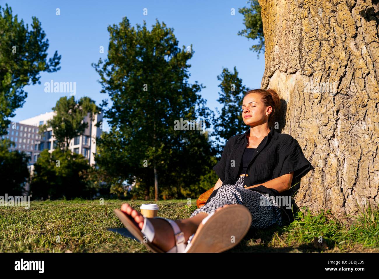 Femme moderne appréciant la pause consciente dans le parc de la ville Banque D'Images