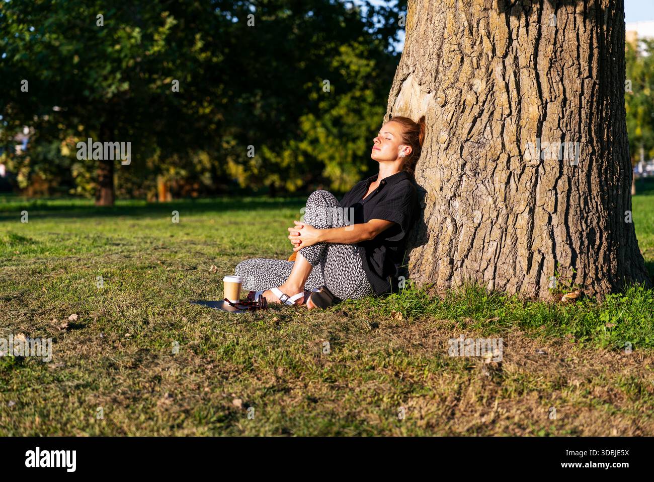 Femme sereine profitant d'une pause consciente dans le parc de la ville. Banque D'Images