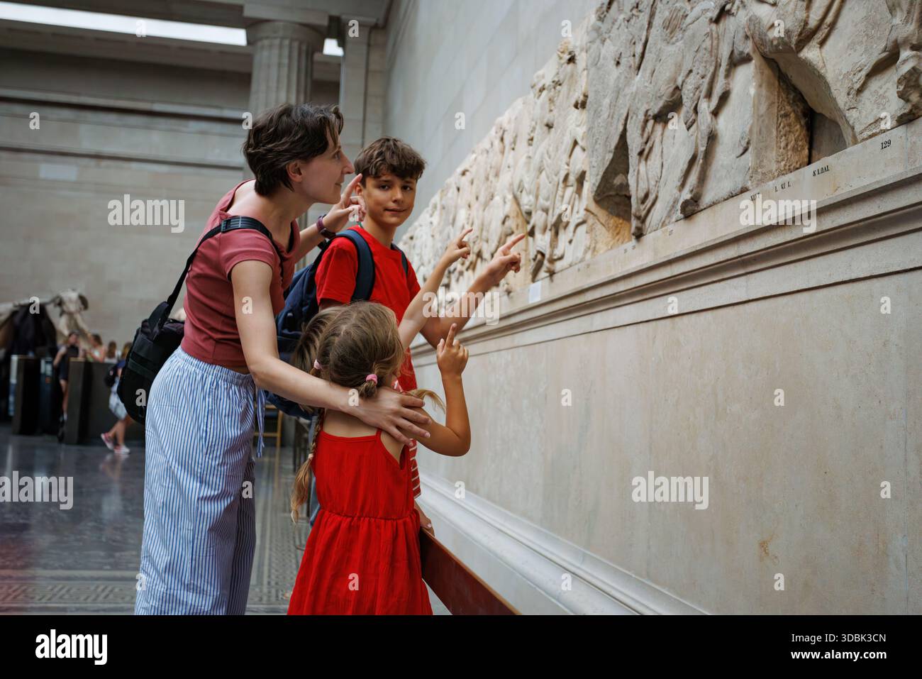 Visite du musée : la famille admire des sculptures en pierre historiques ensemble Banque D'Images