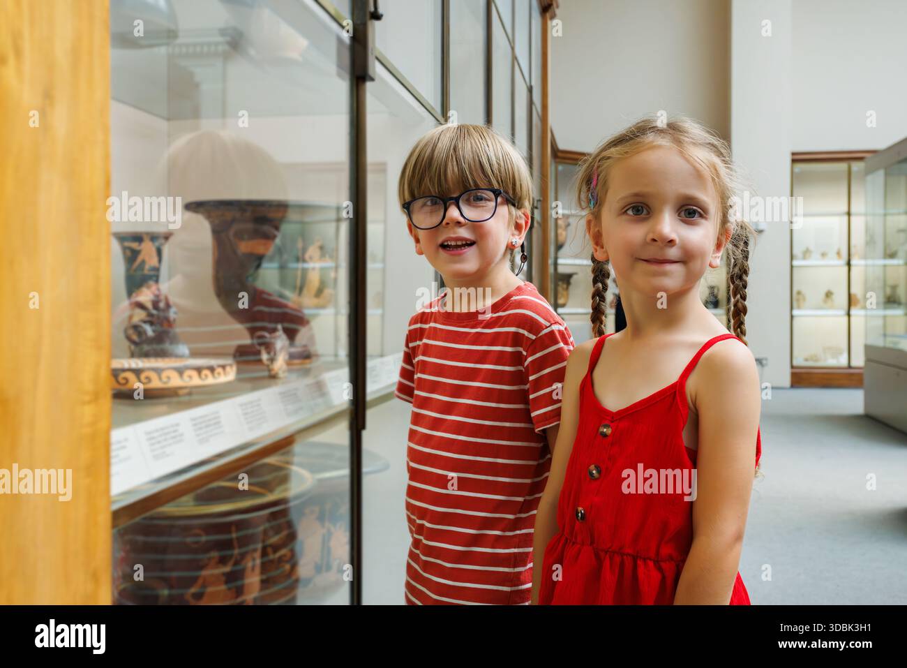 Deux enfants explorateurs admirent des artefacts dans une vitrine de musée Banque D'Images