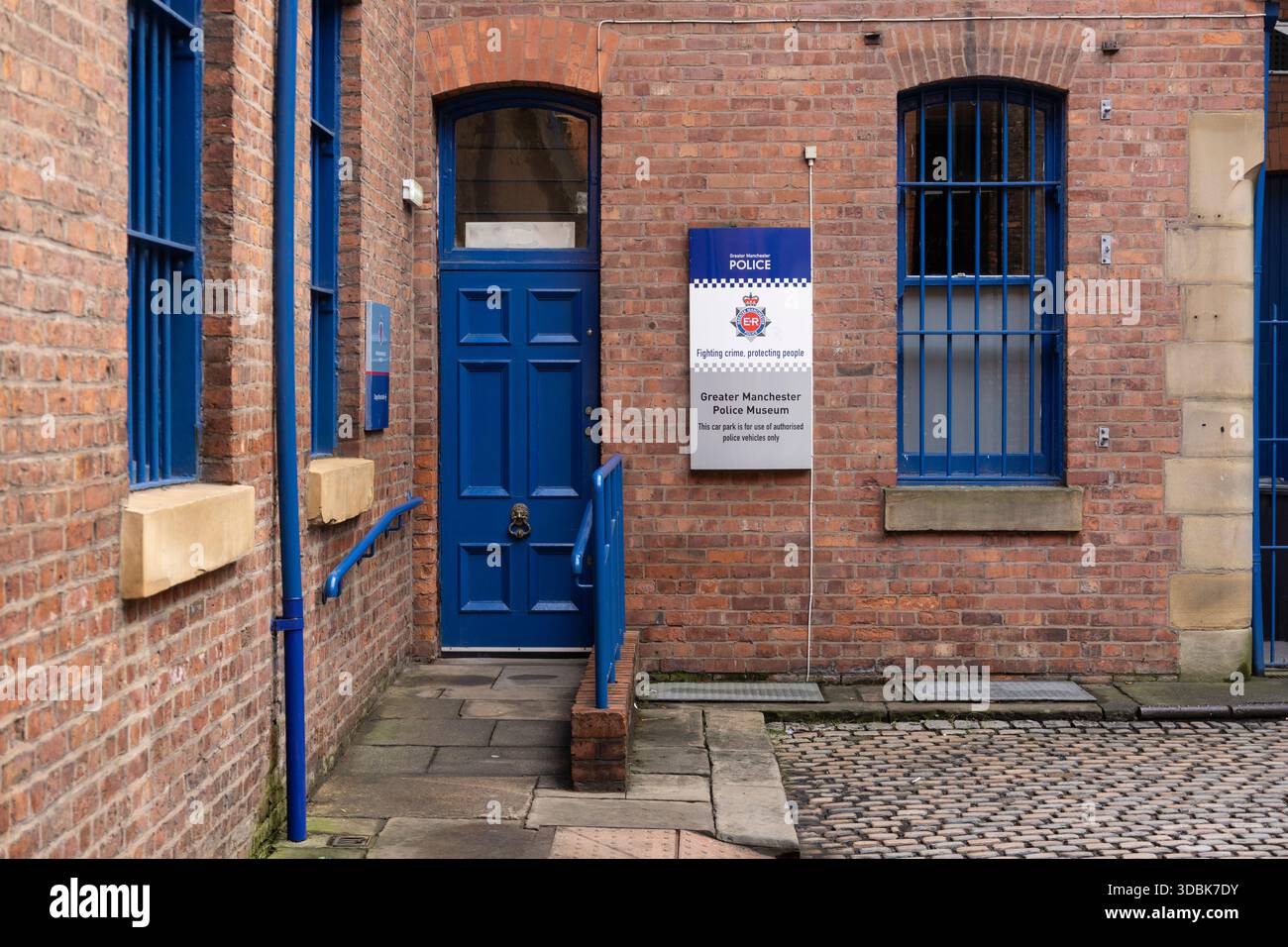 Manchester, royaume-uni, 19 janvier 2025 entrée du musée de la police avec porte bleue sur Brick Building le long de Manchester Cobblestone Street Banque D'Images