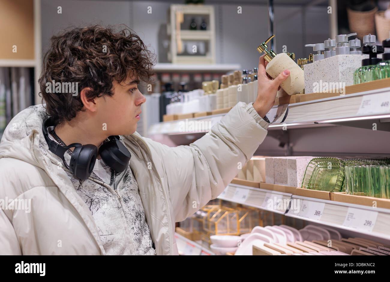 Adolescent choisissant distributeur de savon liquide dans Home Goods Store – Accessoires de salle de bain Shopping. Young Man Shopping pour Accessoires de salle de bain. Intérieur des Banque D'Images