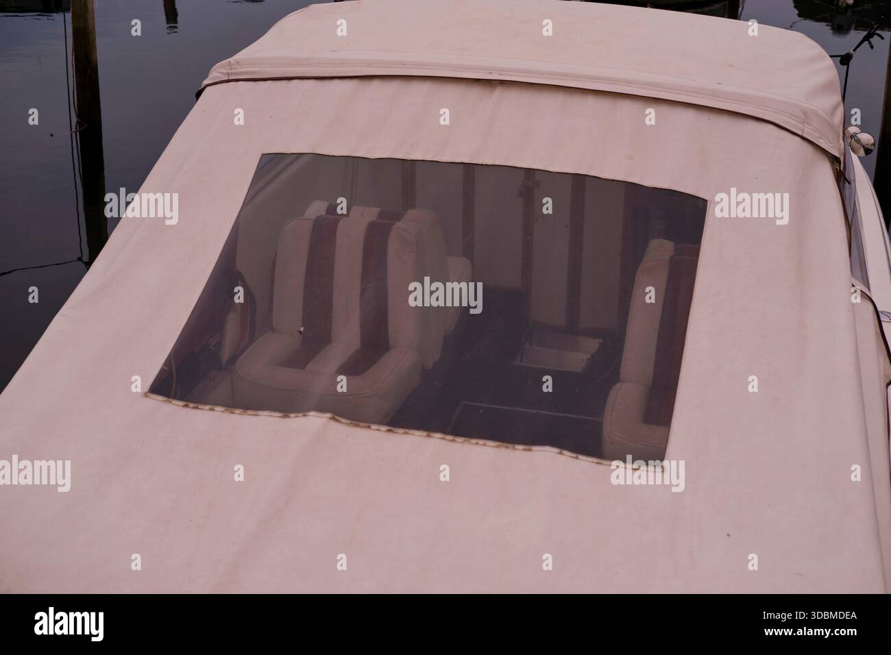 Vue à travers la fenêtre d'un toit de bateau dans l'intérieur du bateau. Vous pouvez voir de petits sièges rayés rouges et blancs. Le bateau de loisirs est ancré et a été photographié depuis la jetée. Gros plan Banque D'Images