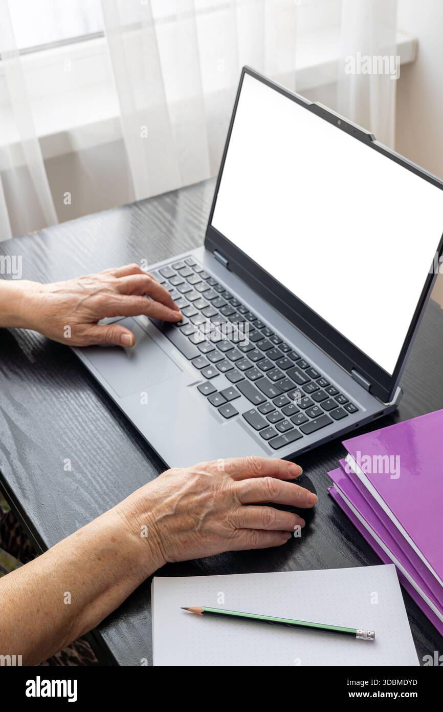 Femme âgée de 70 ans et plus utilisant un ordinateur portable à la maison pour le travail à distance, la communication en ligne et la gestion financière. Concept de vieillissement actif, adoption de la technologie, Banque D'Images