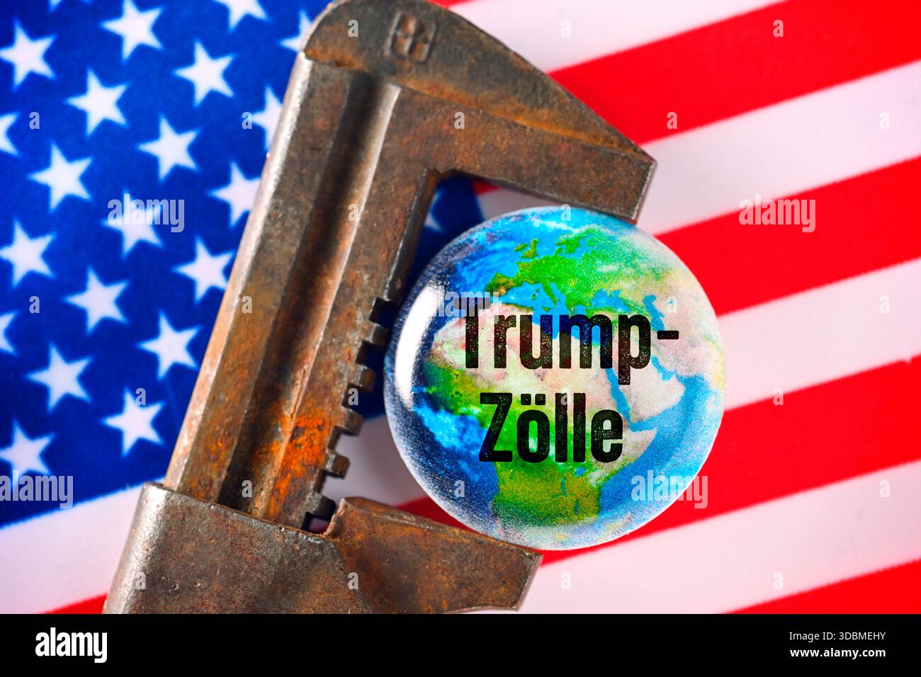 Globe dans la pince avec l’inscription Trump tarifs sur le drapeau américain, photo symbolique pour les tarifs Trump et les conséquences économiques mondiales, photomontage Banque D'Images