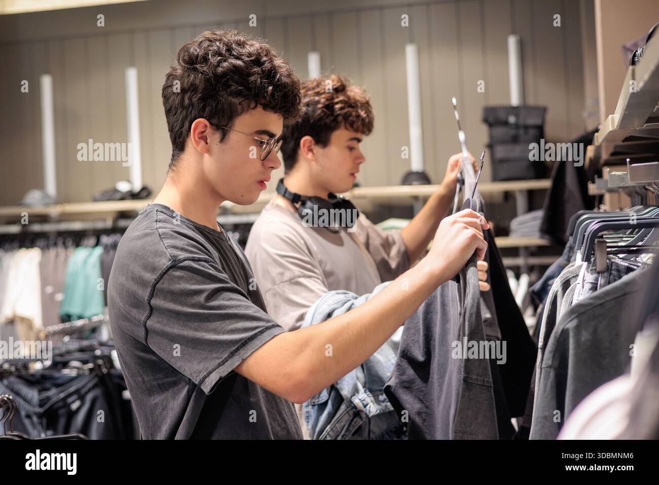 Twin Brothers Shopping pour les vêtements. Amitié jeunesse et mode. Portrait d'adolescents joyeux choisissant des tenues. Generation Z, Urban Fashion et Co Banque D'Images