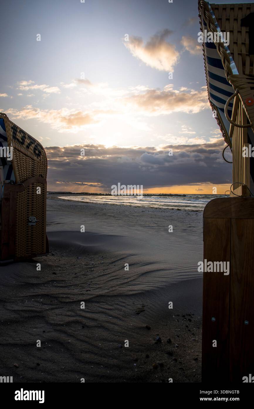 Chaises de plage sur la plage. En arrière-plan, des nuages bleu foncé et un coucher de soleil avec une lumière orange Banque D'Images