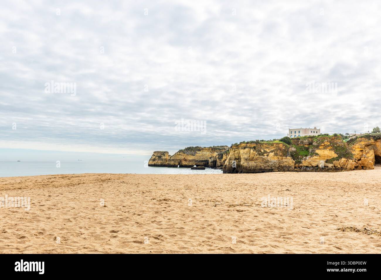 Vue panoramique de Praia da Batata à Lagos, Algarve, Portugal, avec une plage de sable doré, des falaises de calcaire spectaculaires et une ouverture naturelle en arc de roche Banque D'Images