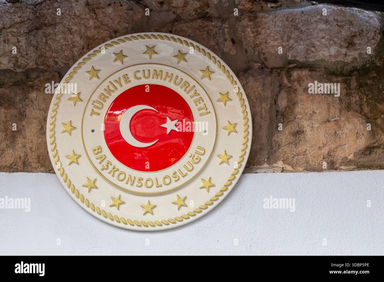 Plaque du Consulat général de la République de Türkiye (Türkiye Cumhuriyeti BaskonsolosluÄŸu), portant l'emblème national avec le croissant et l'étoile, montée sur un mur de pierre Banque D'Images