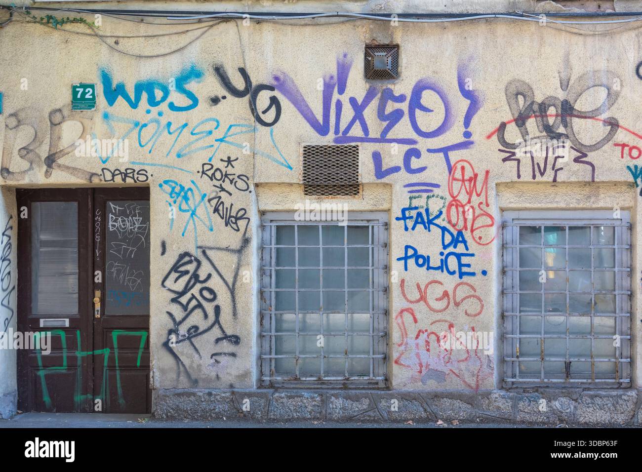 Mur couvert de graffitis avec fenêtres barrées et une porte à Sarajevo, Bosnie-Herzégovine Banque D'Images