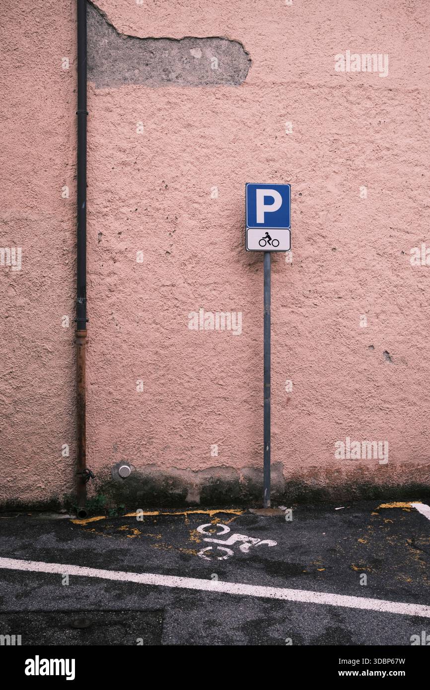 Panneau de stationnement de moto en Italie. Parking d'angle pour motos dans le nord de l'Italie devant une maison de couleur typiquement italienne, dans certains endroits le plâtre est déjà en train de s'effondrer. Banque D'Images