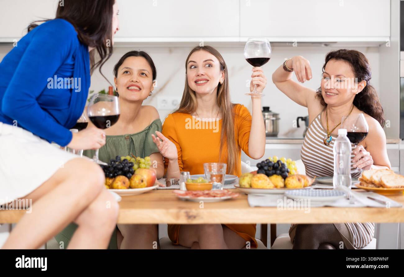 Des femmes heureuses se sont rassemblées autour d'une table festive ; participant à des discussions animées et appréciant les délices du vin Banque D'Images