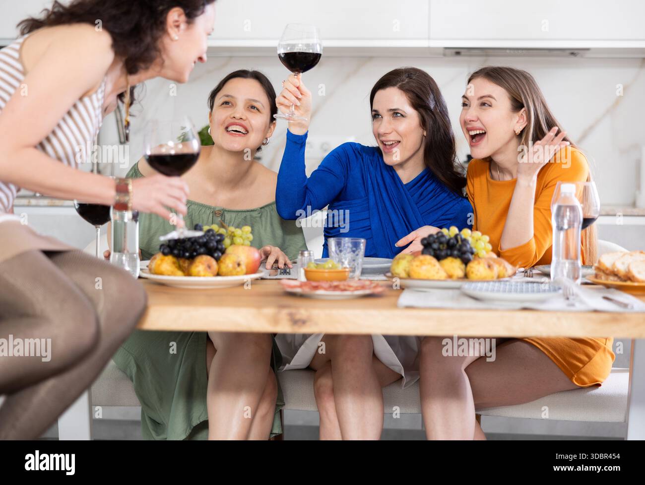 Des femmes heureuses se sont rassemblées autour d'une table festive ; participant à des discussions animées et appréciant les délices du vin Banque D'Images