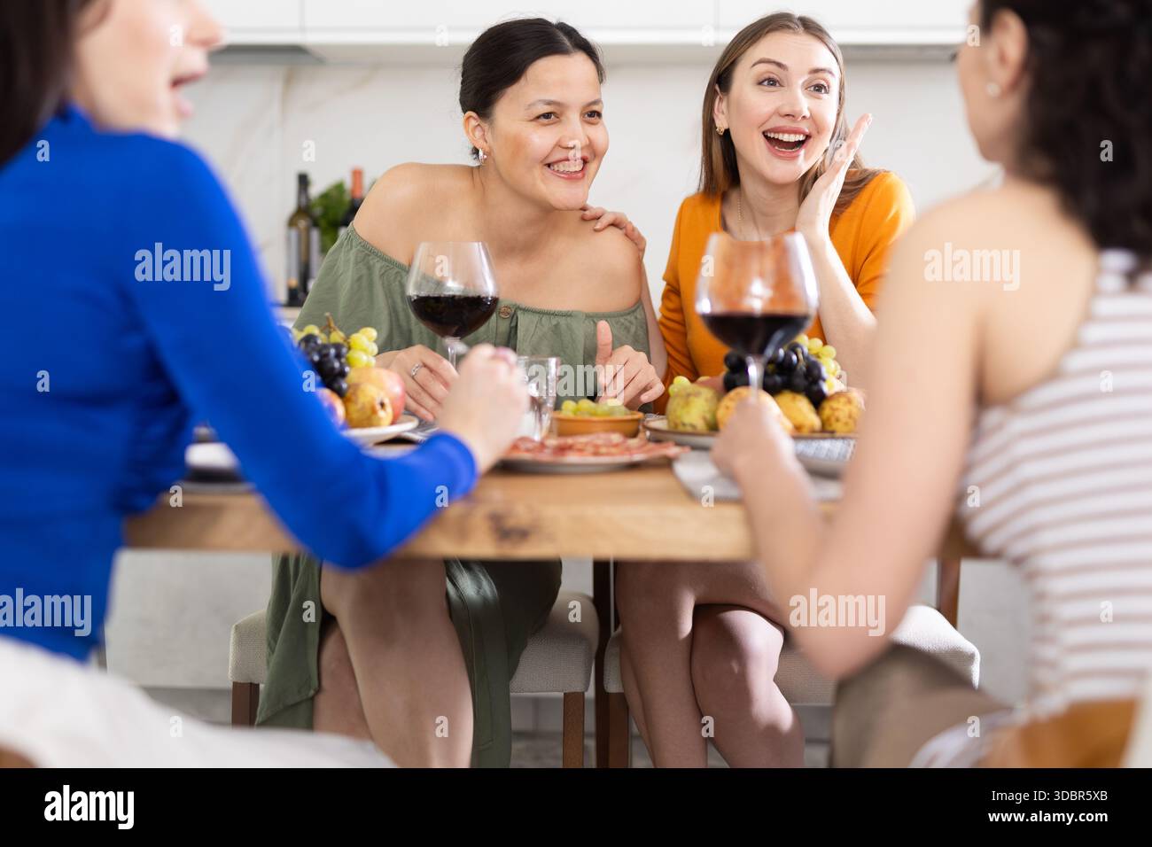 Des femmes heureuses se sont rassemblées autour d'une table festive ; participant à des discussions animées et appréciant les délices du vin Banque D'Images