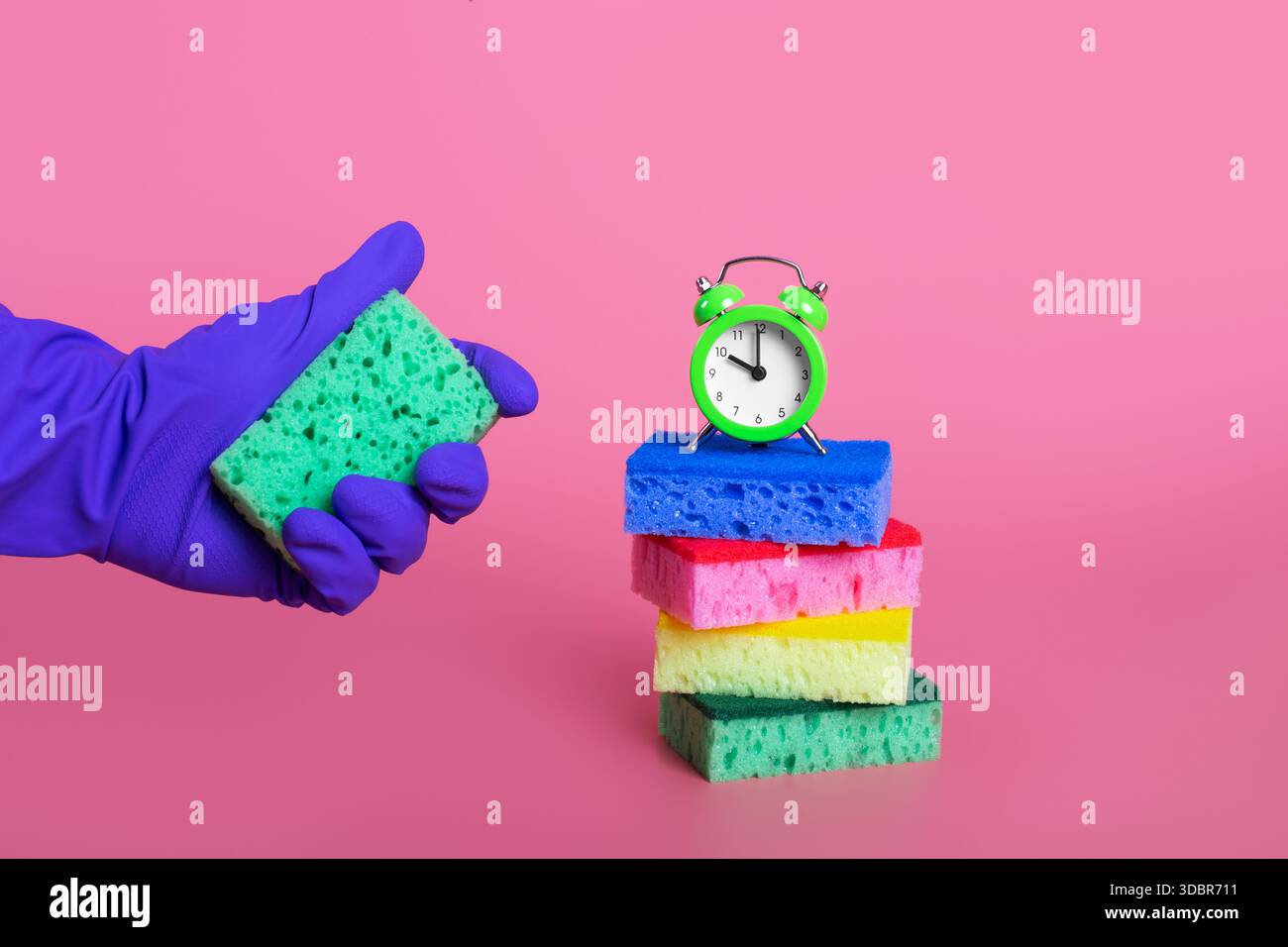 mains dans le gant en caoutchouc violet pressant l'éponge verte sur le concept de nettoyage de fond rose pastel isolé Banque D'Images