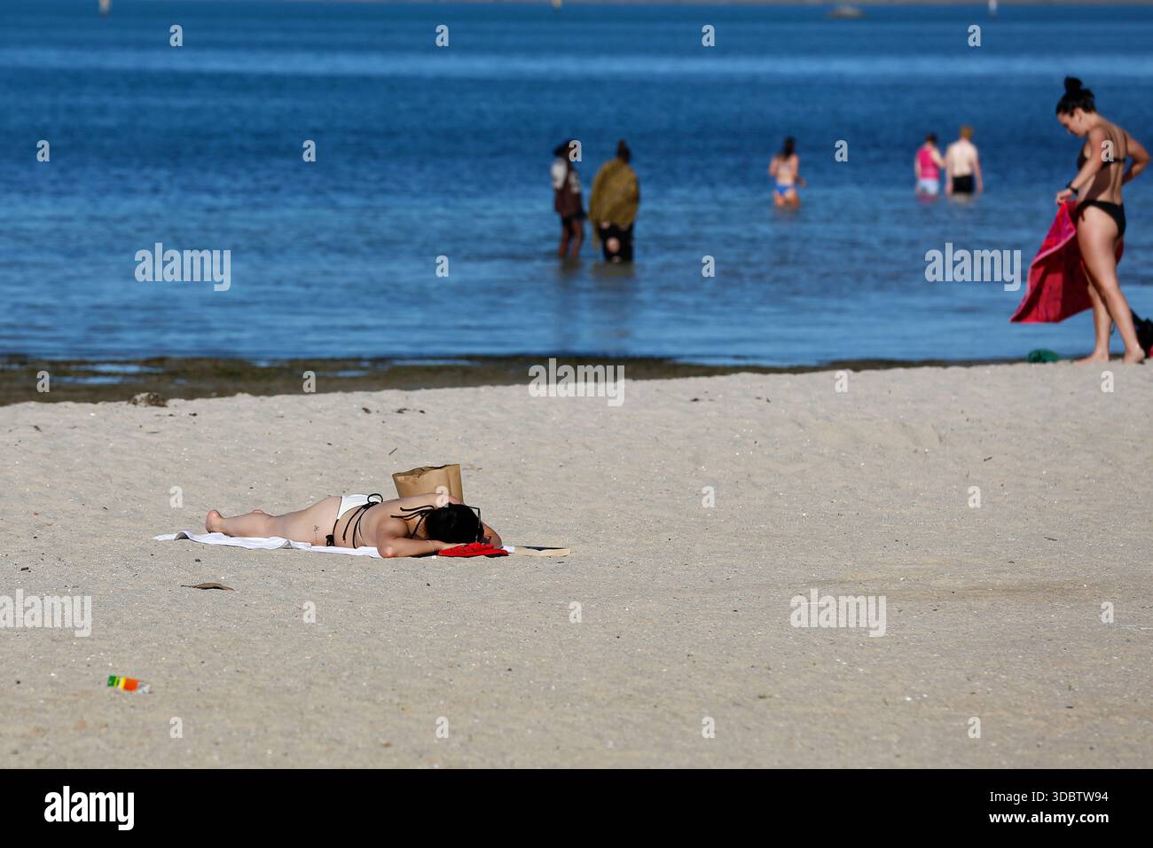 Geelong, Australie. 18 décembre 2025. Une femme est allongée sur le sable en train de bronzer à Geelong Beach par temps chaud. Les gens se rassemblent à Geelong Beach alors que Victoria subit une chaleur extrême, Melbourne atteignant un maximum de 36 °C aujourd'hui. Les conditions chaudes devraient se poursuivre, Melbourne devrait atteindre environ 33 °C demain. Le Bureau of Meteorology a émis un avertissement de vague de chaleur grave pour Victoria, conseillant aux résidents de rester hydratés, de limiter l'exposition au soleil et de suivre les directives sur la chaleur et la santé. Crédit : SOPA images Limited/Alamy Live News Banque D'Images