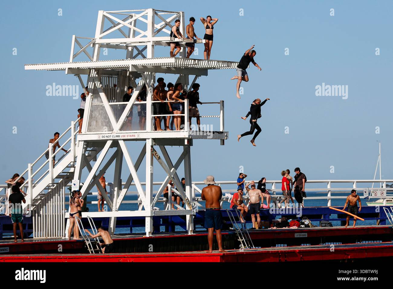 Geelong, Australie. 18 décembre 2025. Les amateurs de plage sont vus sauter dans l'eau à Geelong Beach par temps chaud. Les gens se rassemblent à Geelong Beach alors que Victoria subit une chaleur extrême, Melbourne atteignant un maximum de 36 °C aujourd'hui. Les conditions chaudes devraient se poursuivre, Melbourne devrait atteindre environ 33 °C demain. Le Bureau of Meteorology a émis un avertissement de vague de chaleur grave pour Victoria, conseillant aux résidents de rester hydratés, de limiter l'exposition au soleil et de suivre les directives sur la chaleur et la santé. Crédit : SOPA images Limited/Alamy Live News Banque D'Images