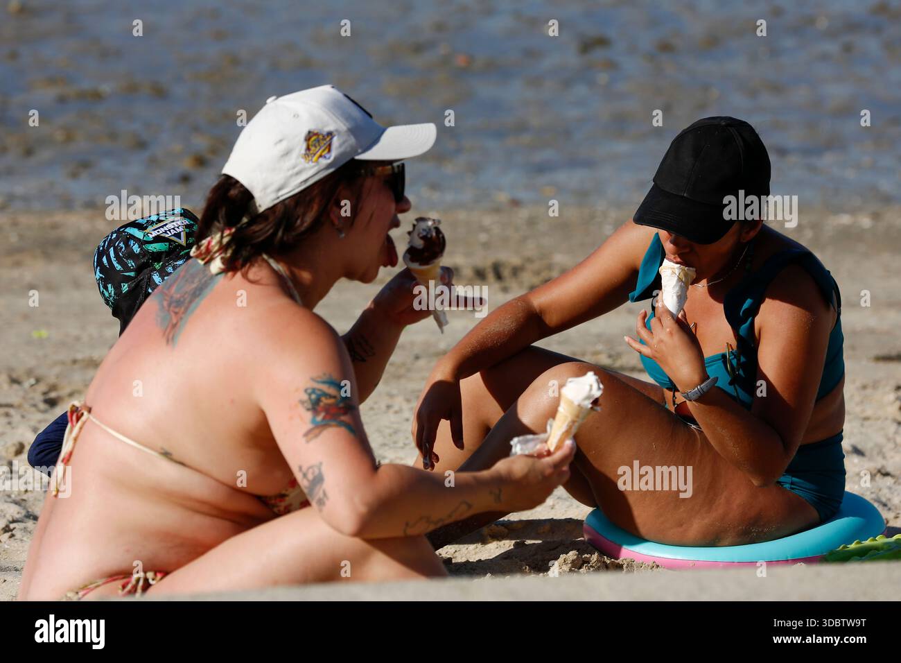 Geelong, Australie. 18 décembre 2025. Deux femmes ont été vues en train d'avoir un brise-glace à Geelong Beach par temps chaud. Les gens se rassemblent à Geelong Beach alors que Victoria subit une chaleur extrême, Melbourne atteignant un maximum de 36 °C aujourd'hui. Les conditions chaudes devraient se poursuivre, Melbourne devrait atteindre environ 33 °C demain. Le Bureau of Meteorology a émis un avertissement de vague de chaleur grave pour Victoria, conseillant aux résidents de rester hydratés, de limiter l'exposition au soleil et de suivre les directives sur la chaleur et la santé. Crédit : SOPA images Limited/Alamy Live News Banque D'Images
