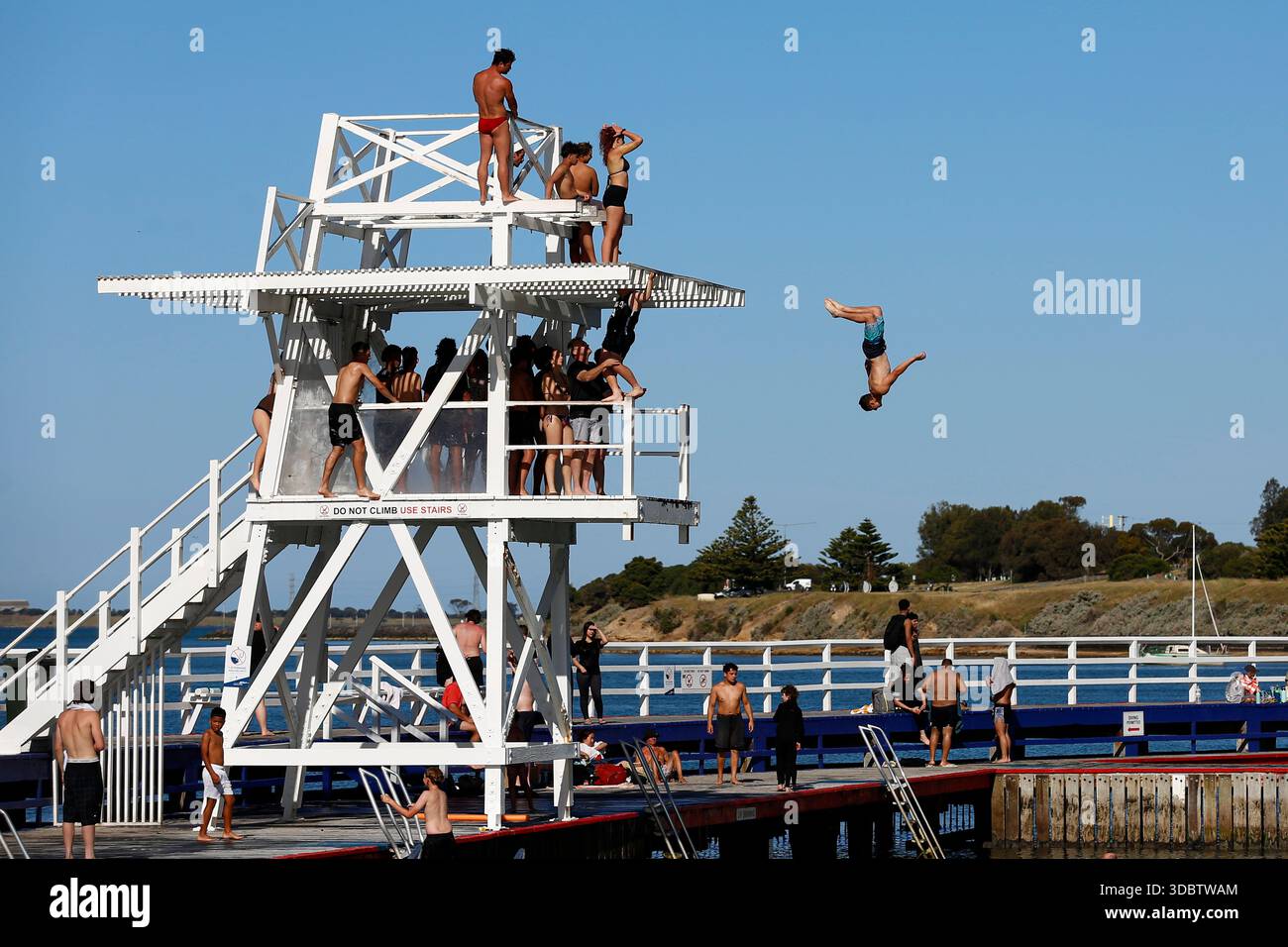 Geelong, Australie. 18 décembre 2025. Un homme plonge dans l'eau à Geelong Beach par temps chaud. Les gens se rassemblent à Geelong Beach alors que Victoria subit une chaleur extrême, Melbourne atteignant un maximum de 36 °C aujourd'hui. Les conditions chaudes devraient se poursuivre, Melbourne devrait atteindre environ 33 °C demain. Le Bureau of Meteorology a émis un avertissement de vague de chaleur grave pour Victoria, conseillant aux résidents de rester hydratés, de limiter l'exposition au soleil et de suivre les directives sur la chaleur et la santé. Crédit : SOPA images Limited/Alamy Live News Banque D'Images