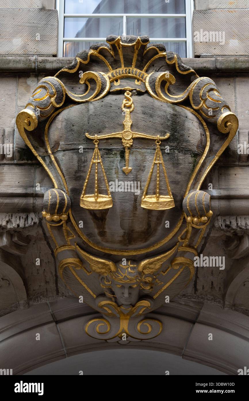 Écailles dorées de justice sur façade en pierre ornée - relief héraldique au-dessus de l'entrée du palais de justice Banque D'Images