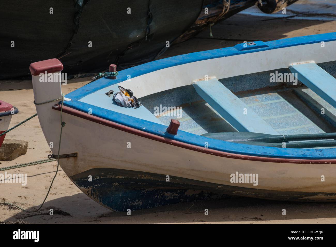Un bateau de pêche portugais rouge, blanc et bleu sur la plage de Cabanas, Algarve, Portugal Banque D'Images