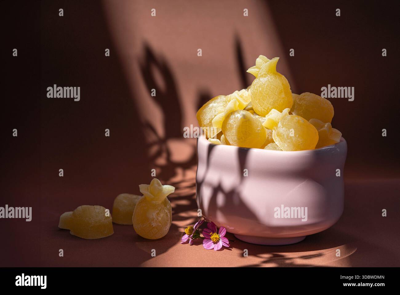 Gelée croustillante hai ou Voon Krob en forme d'ananas servie dans un bol rose. Belle lumière naturelle du soleil et ombre sur fond brun avec des aliments créatifs s Banque D'Images