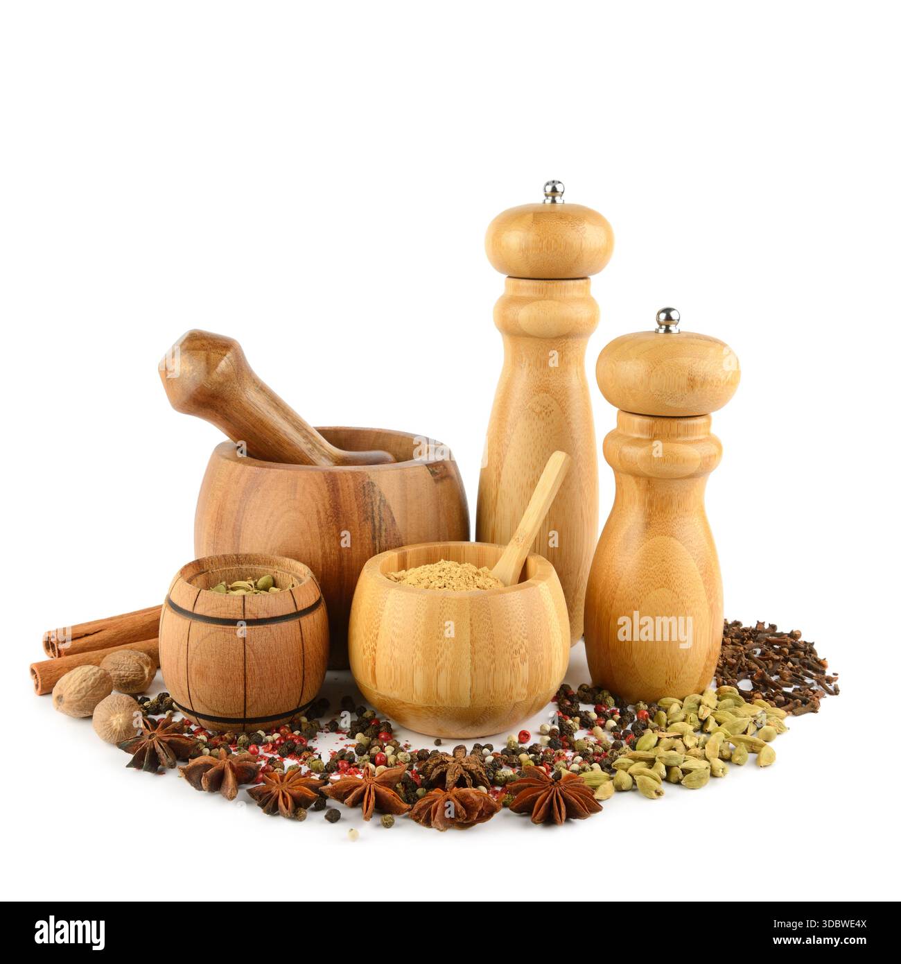 Une collection d'outils de cuisine en bois entourés d'épices entières vibrantes sur un fond blanc propre. Banque D'Images