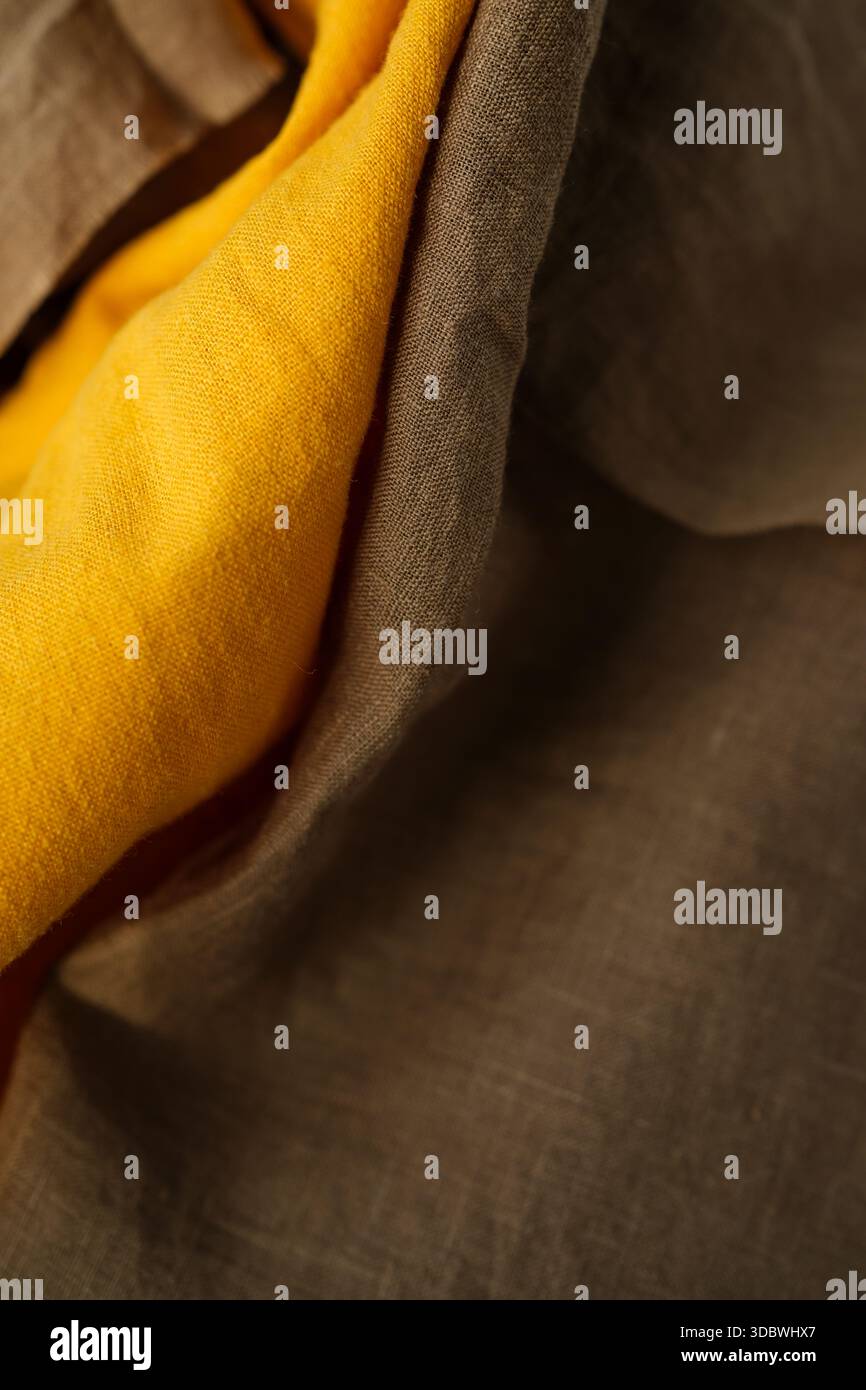 Tissu de lin brun et jaune chaud placé au hasard. Brun foncé et jaune moutarde doré. Maquette tissu lin. Faible profondeur de champ. Copier l'espace Banque D'Images