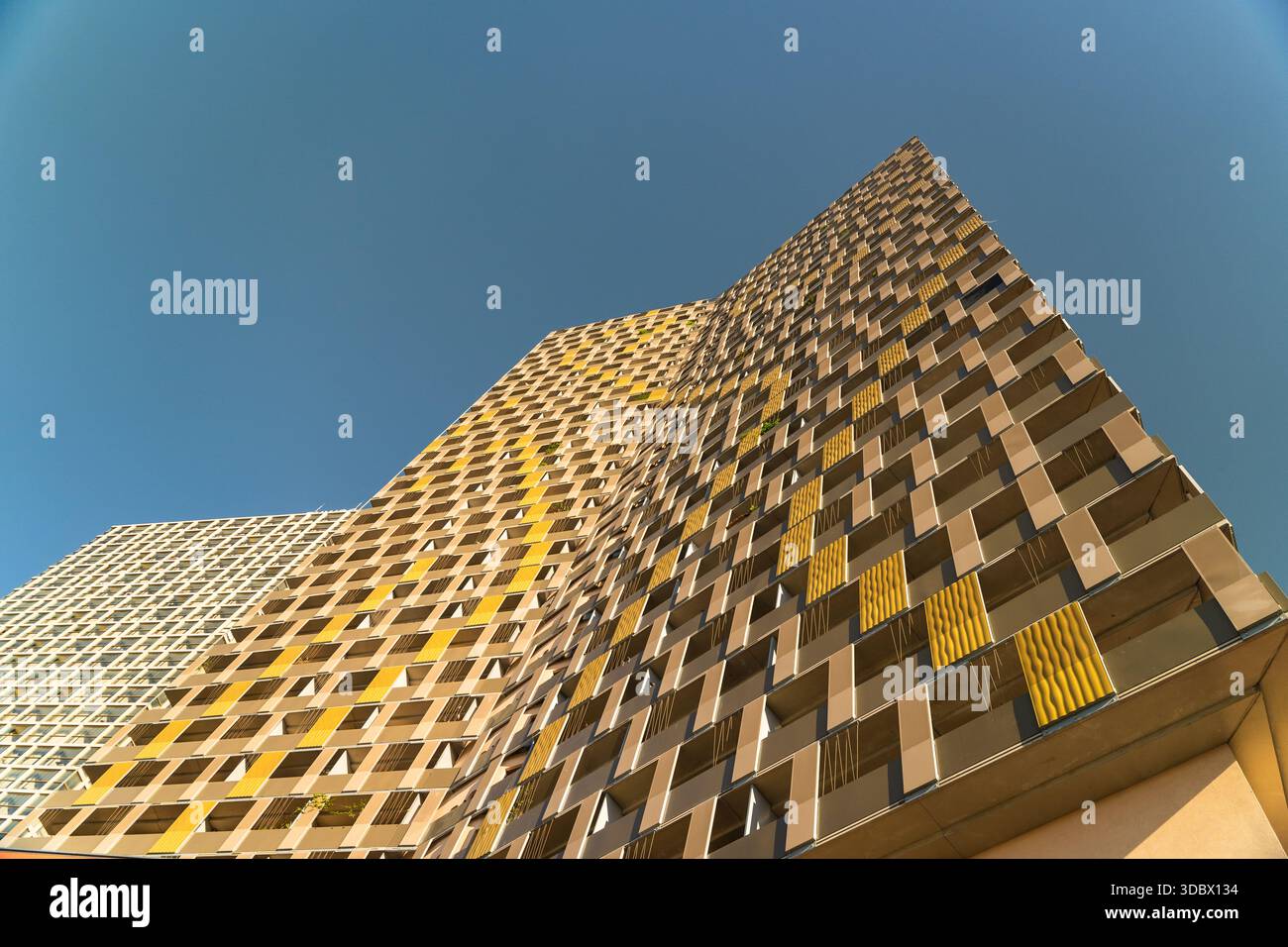 Vue d'un immeuble moderne de grande hauteur avec une façade géométrique de jaune doré et marron contre un ciel bleu clair et vibrant, Vienne, Vienne, Autriche. Banque D'Images