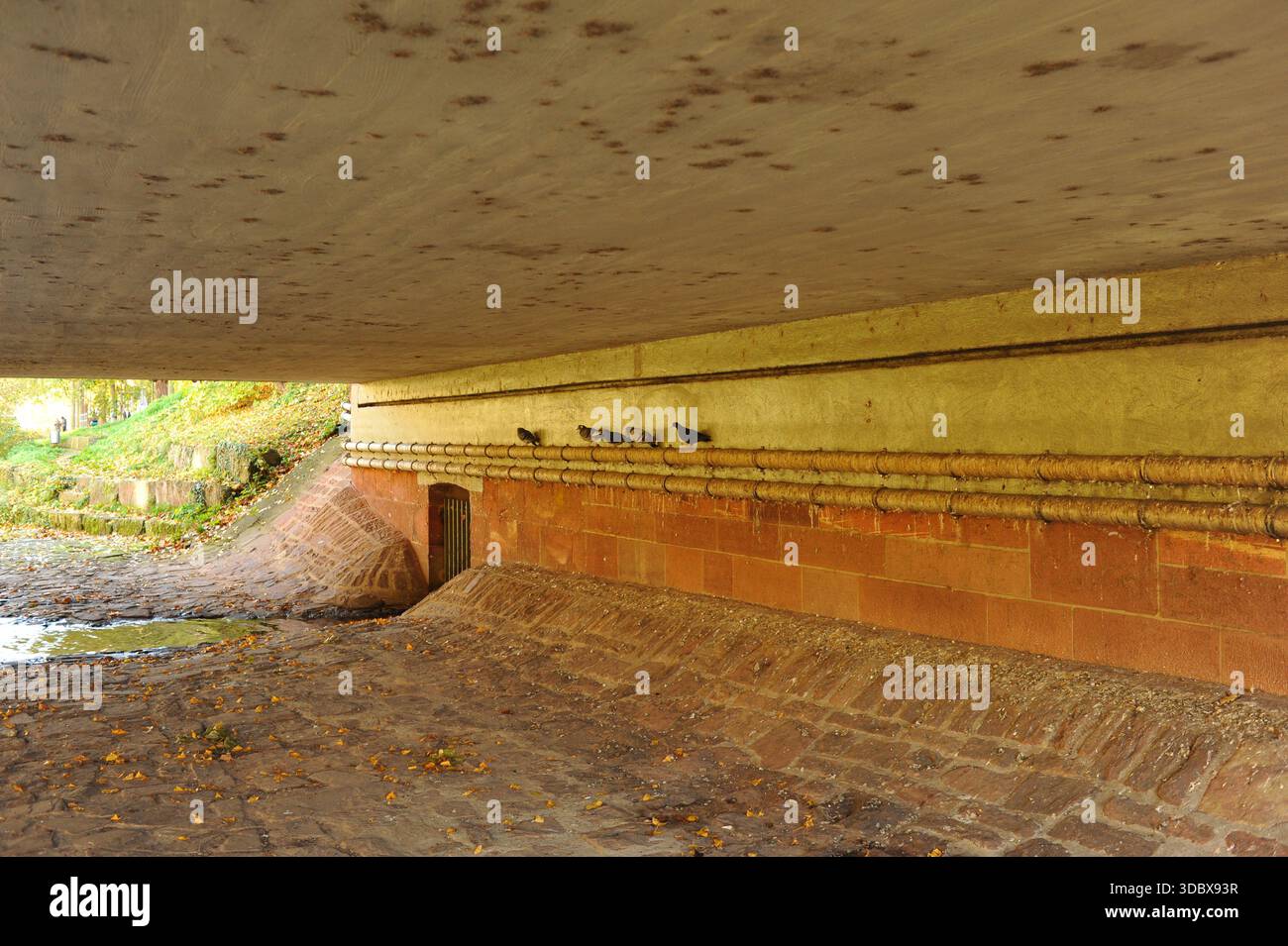 Pforzheim, Allemagne Dezember pont ombragé passage inférieur chemin pavé du canal montrant plafond en béton humide avec des taches d'eau brunes, rouge Banque D'Images