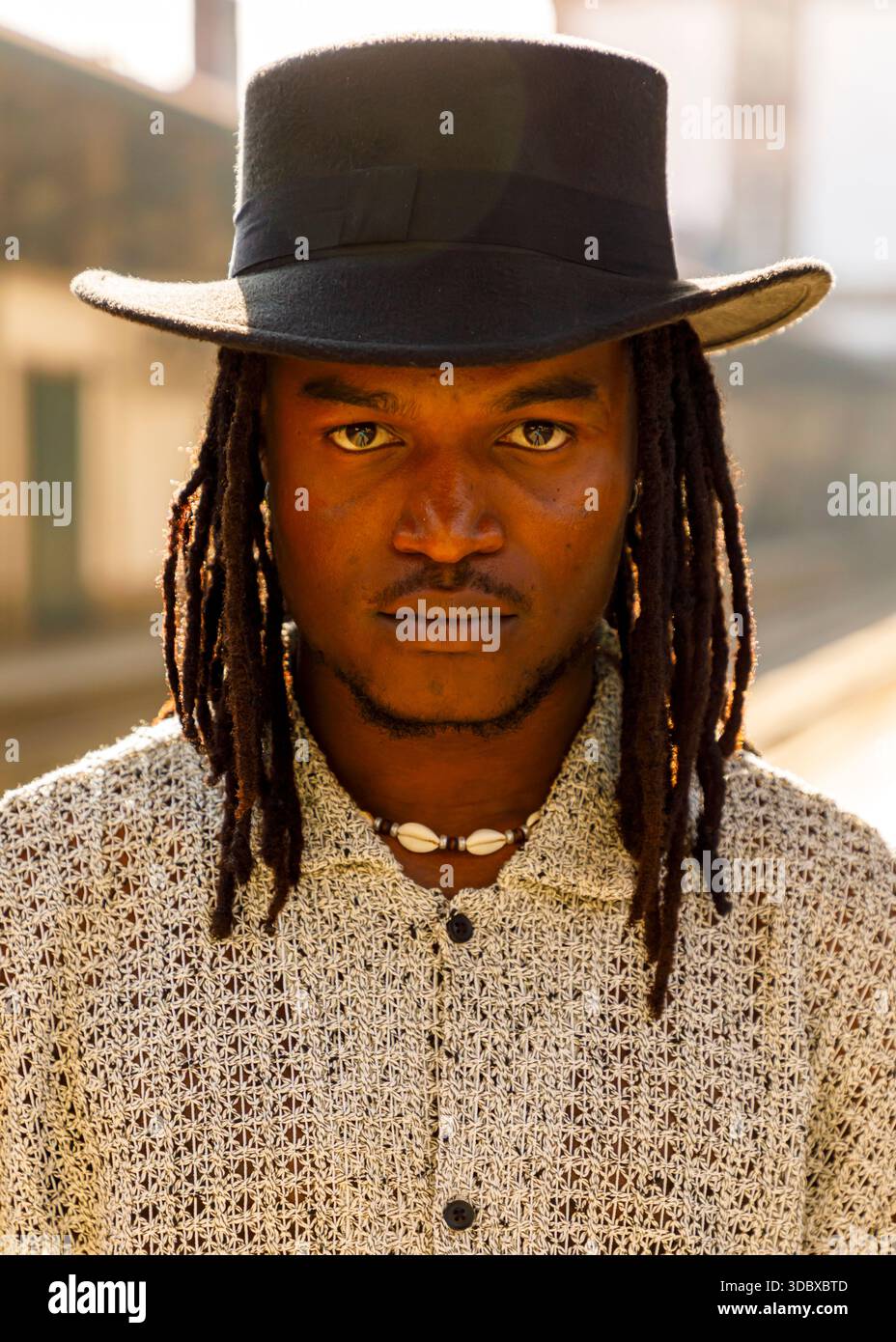 Un homme avec des dreadlocks et un chapeau noir regarde directement la caméra. Banque D'Images