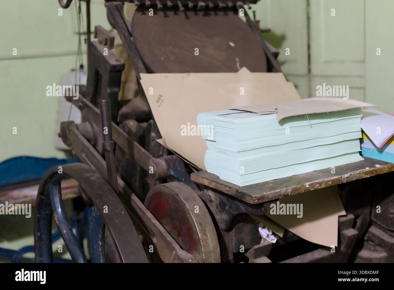 Une presse à imprimer se trouve dans un atelier avec des piles de papier prêtes à l'emploi. Banque D'Images