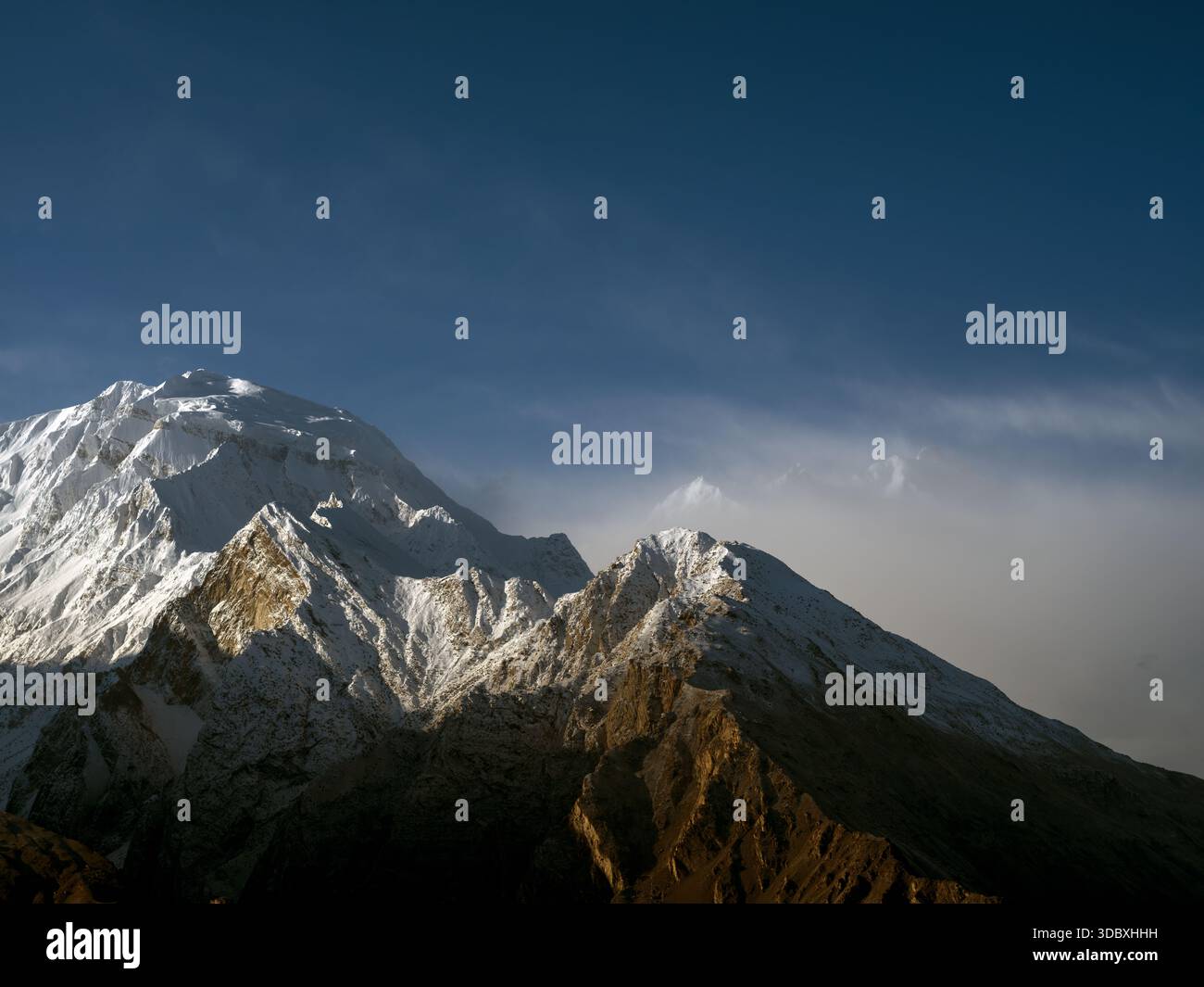 Vue sur les montagnes enneigées s'élèvent majestueusement contre un ciel bleu clair, leurs sommets embrassés par la lumière du soleil, créant un contraste étonnant de lumière et de sh Banque D'Images