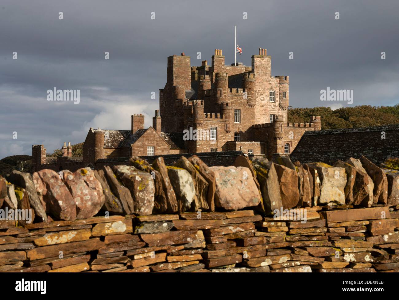 L'ancien château s'élève derrière un mur de pierre empilé sous un ciel sombre et couvert. Banque D'Images