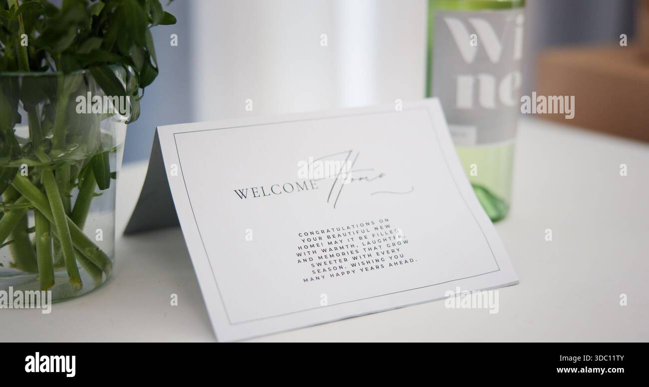 Nouvelle maison, note et bienvenue avec carte sur table dans l'appartement pour félicitations ou message. Investissement, propriété et immobilier avec lettre de voeux Banque D'Images