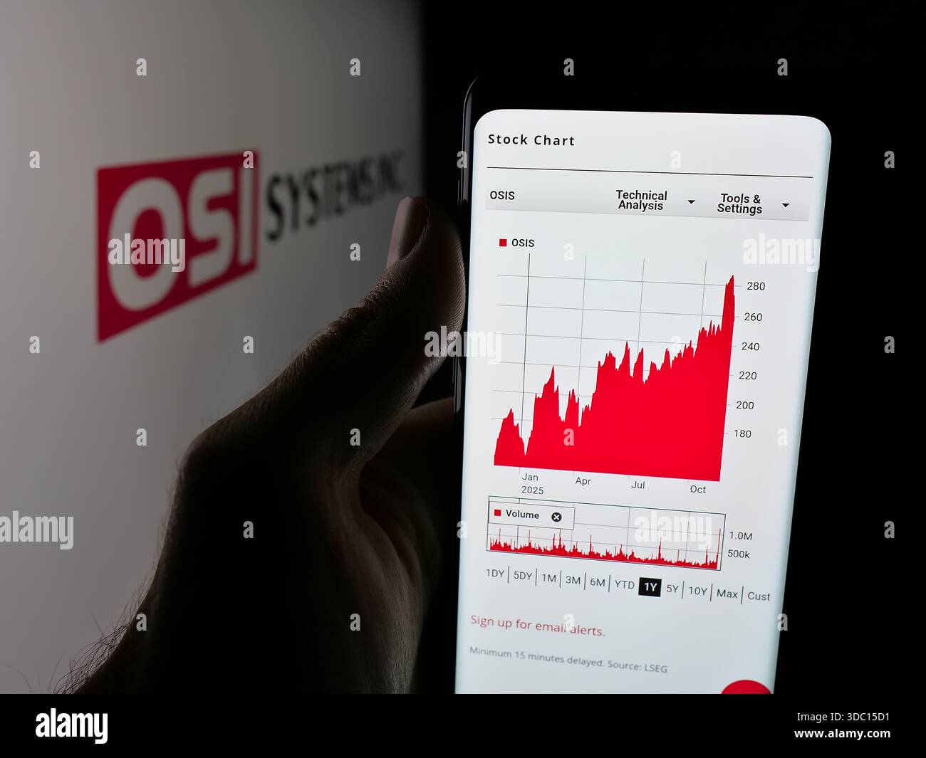 Dans cette illustration photo, une personne tient un téléphone portable avec la page Web de la société de sécurité américaine OSI Systems Inc sur l'écran devant le logo. Banque D'Images