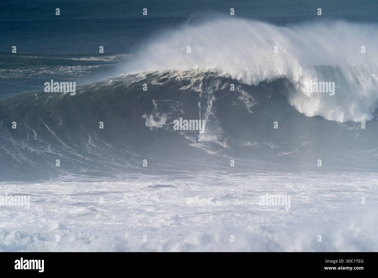 Scène dramatique d'un surfeur chevauchant une grosse vague à Nazaré, au Portugal, photographiée à Praia do Norte, connue pour le surf de grande vague de classe mondiale. Banque D'Images