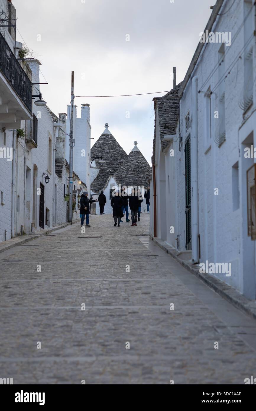 Arberobello, italie, 29 novembre 2025. longue vue sur la rue étroite des maisons emblématiques alberobello trulli avec leurs toits coniques, montrant quelques lointains Banque D'Images