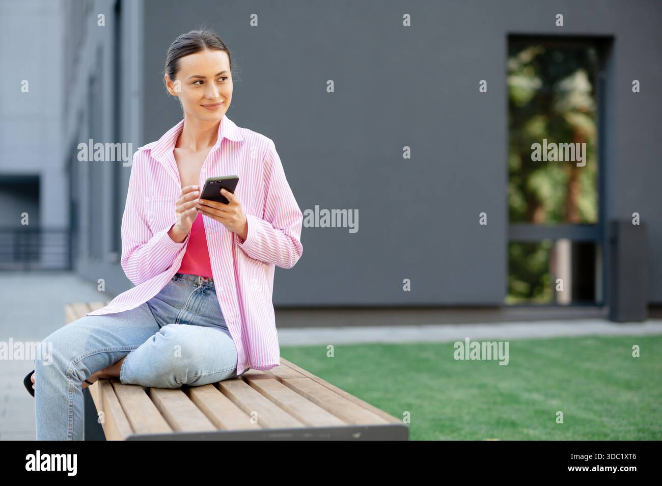 Femme utilisant smartphone sur le banc extérieur Banque D'Images