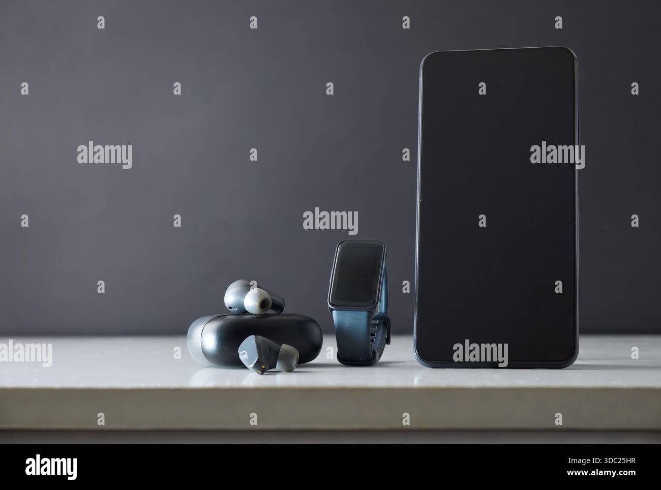 Détail de smartwatch smartphone et écouteurs sans fil sur la table blanche isolée gris. Vue de face. Banque D'Images