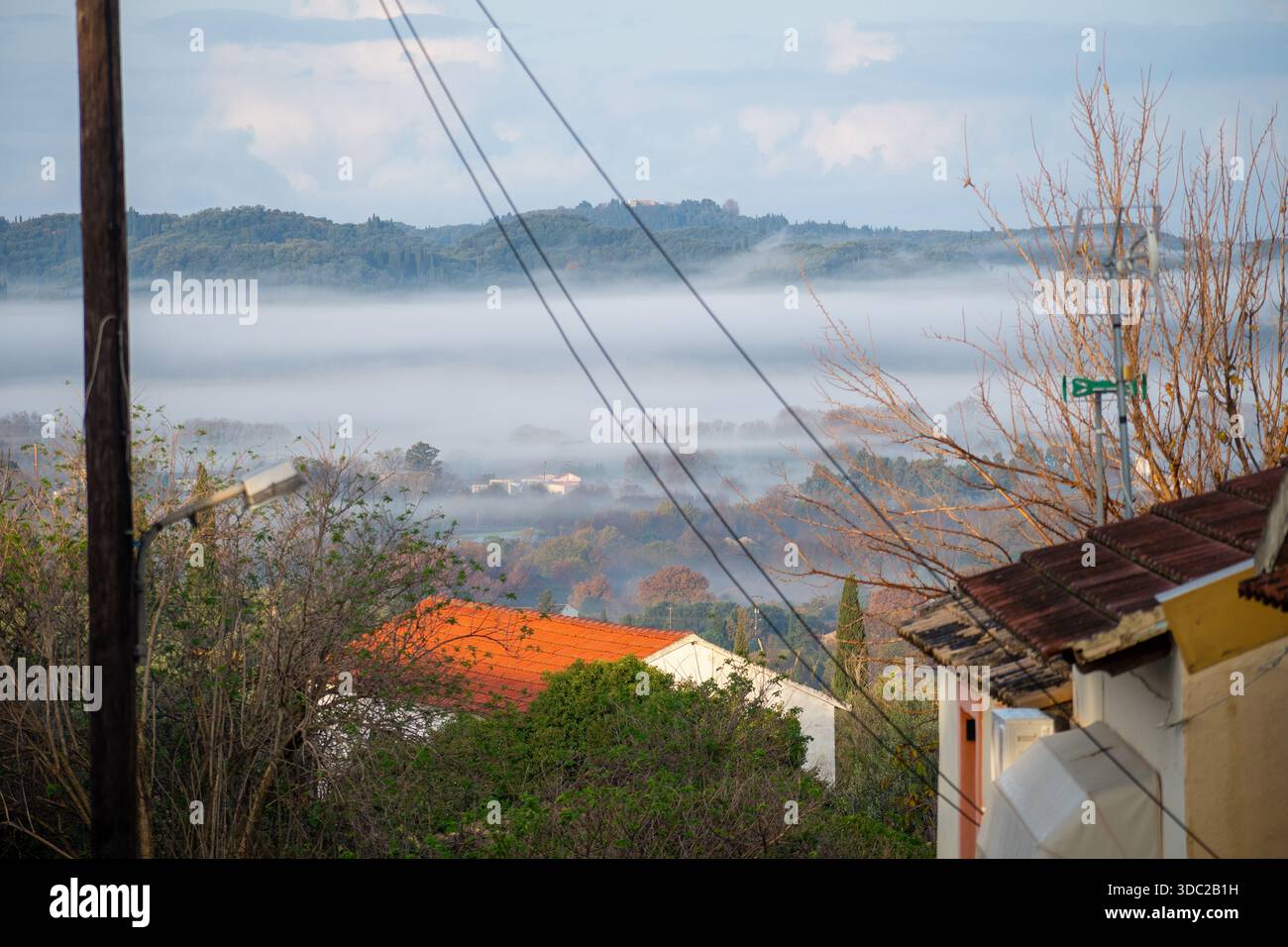Maison de village grecque rurale avec tuiles de toit orange donnant sur une vallée brumeuse à Corfou Banque D'Images