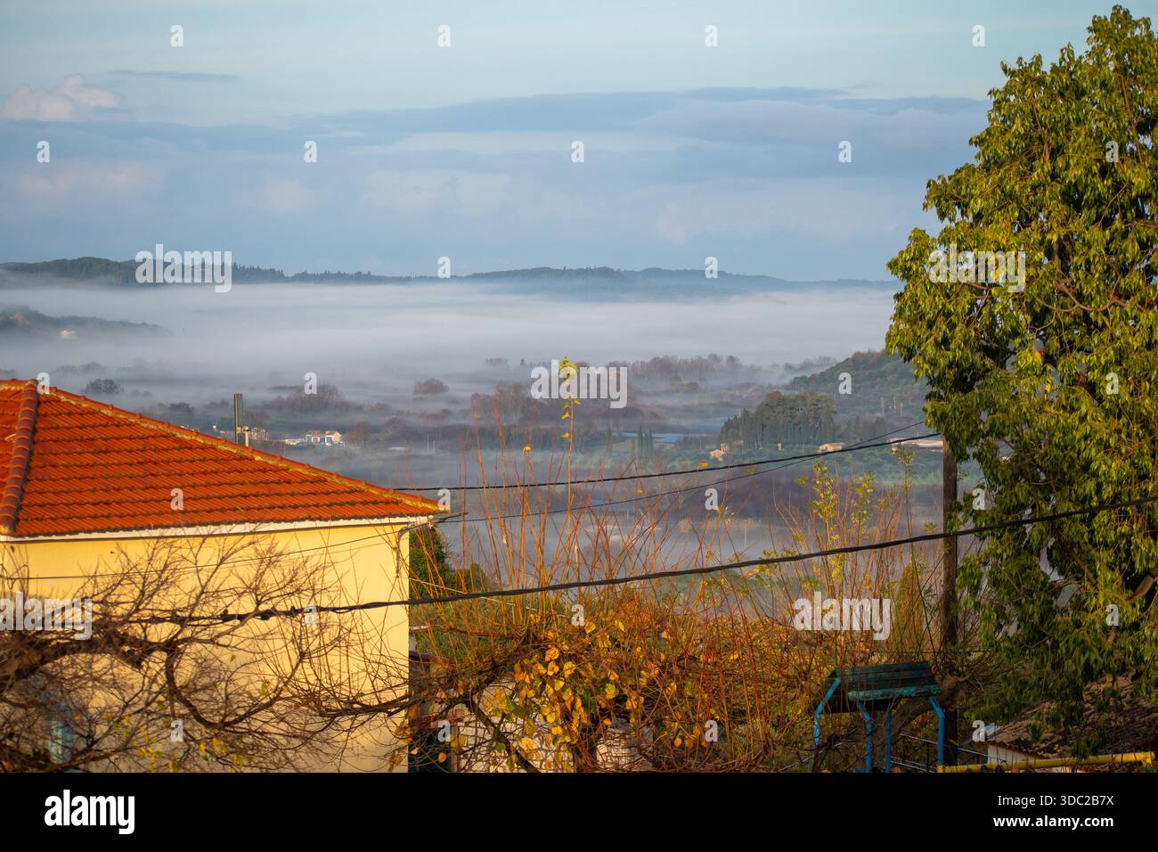 Maison de campagne jaune et feuillage d'automne sur fond de collines de Foggy à Corfou en Grèce Banque D'Images