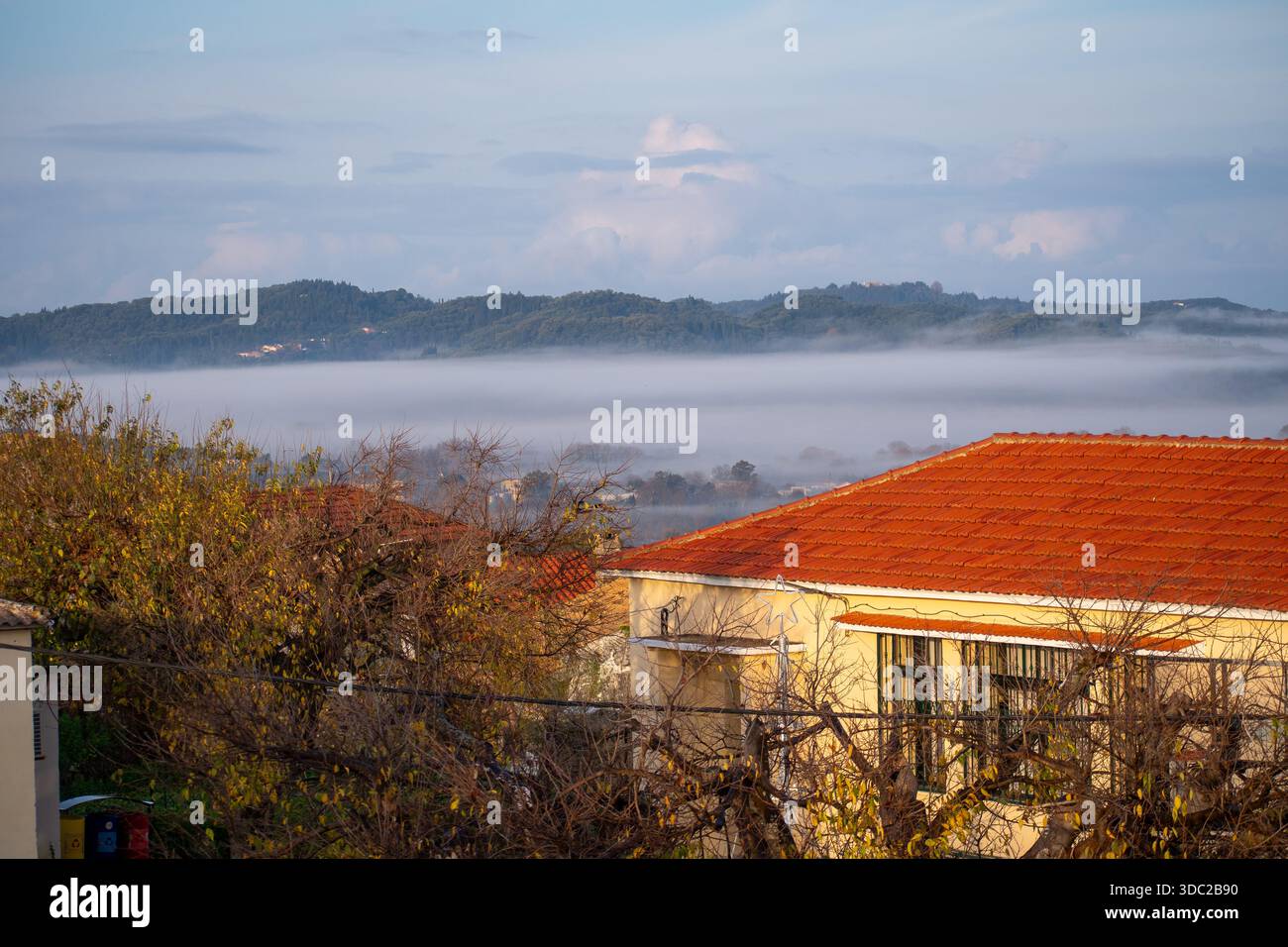 Toiture carrelée traditionnelle au premier plan avec Heavy Morning Mist couvrant le paysage de Corfou Banque D'Images