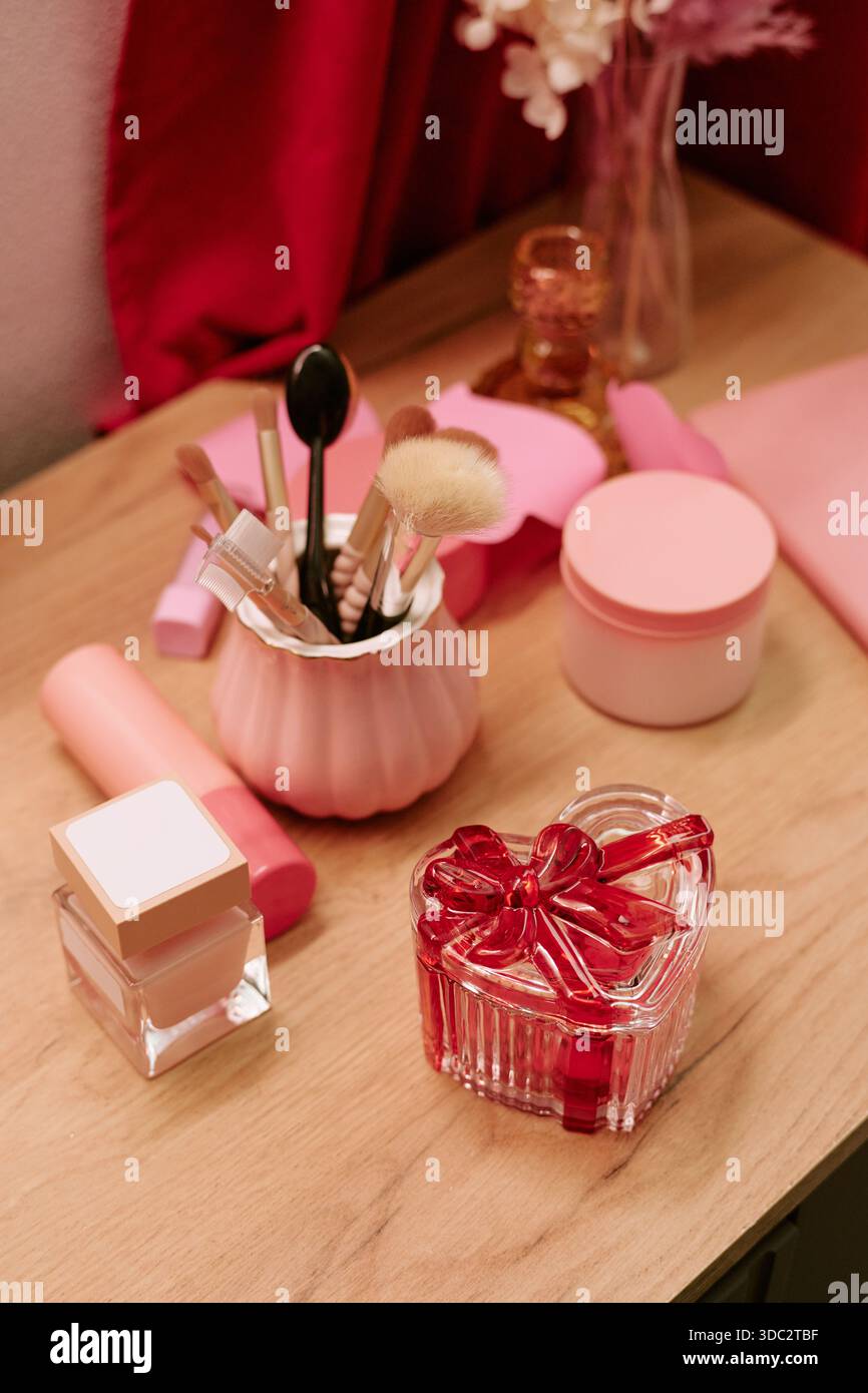 Boîte en verre en forme de coeur et produits de maquillage disposés pour la Saint-Valentin Banque D'Images
