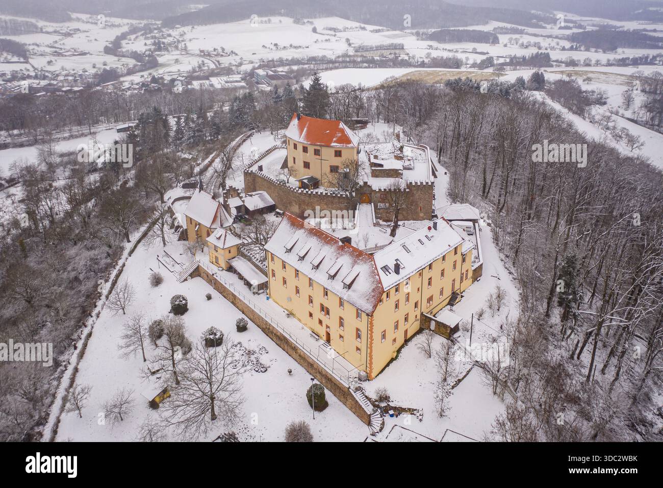 Vue aérienne du Schloss Reichenberg enneigé, un château médiéval aux toits rouges contrastant avec le paysage blanc de Reichelsheim (Oden Banque D'Images