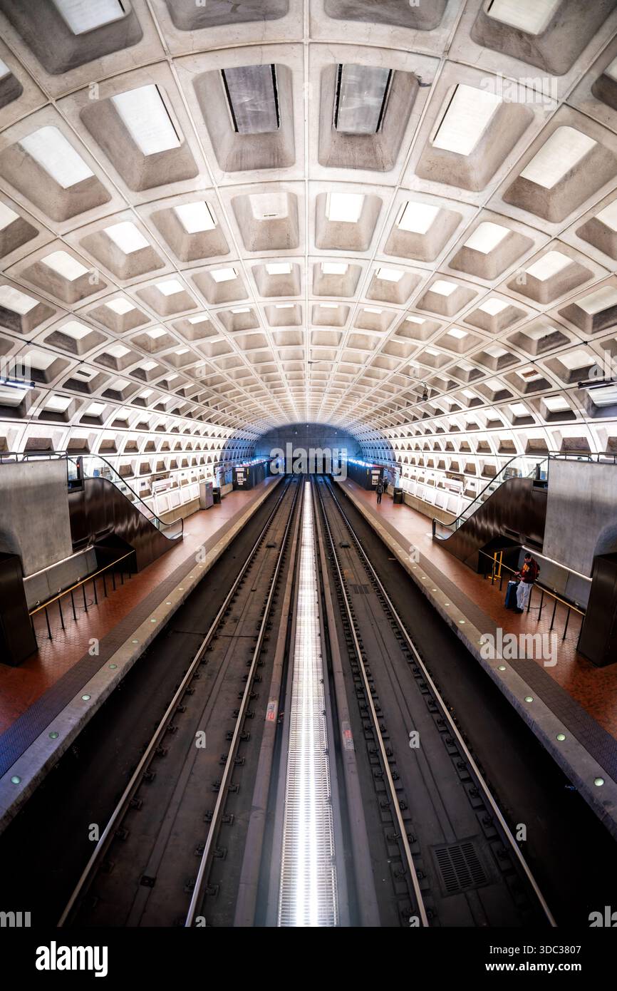 Crystal City Metro Station Arlington Virginie // ARLINGTON, Virginie — la station de métro Crystal City à Arlington, Virginie, présente l'architecture brutaliste emblématique du métro de Washington. Son grand plafond en béton arqué présente un design à caissons distinctif, caractéristique de la vision de l'architecte Harry Weese. Inaugurée le 1er juillet 1977, la station dessert les lignes bleue et jaune de la Washington Metropolitan Area transit Authority (WMATA). Les plates-formes caverneuses sans colonne et le béton apparent sont caractéristiques de l'esthétique unique du système. C'est un centre de transport vital fo Banque D'Images