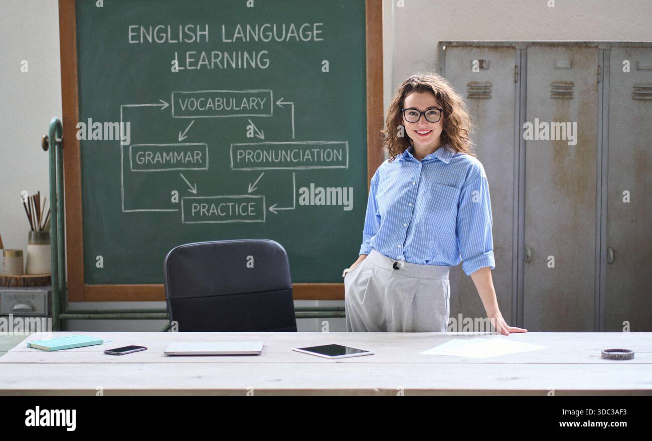 Jeune femme enseignante debout à un bureau devant le tableau de surveillance en classe. Banque D'Images