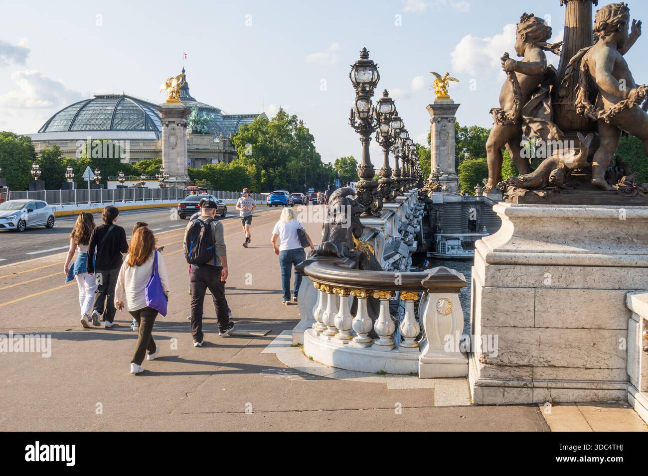 Paris, France - 15 juin 2025 : touristes marchant sur le pont Alexandre-III de l'autre côté de la Seine à Paris. Pont décoré de lampes Art nouveau ornées Banque D'Images
